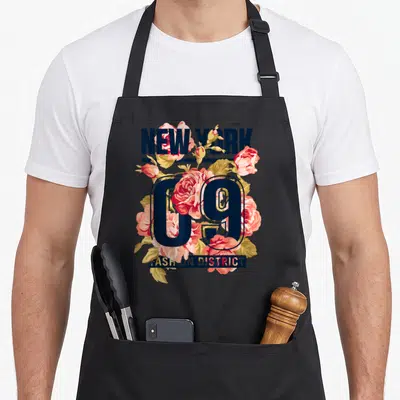 Tablier de cuisine noir avec inscription New York 09 Fashion District et bouquet de roses roses et feuilles dorées.