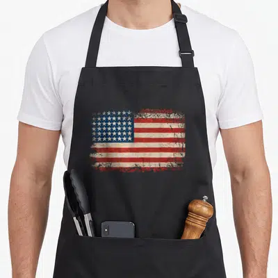 Tablier de cuisine noir avec un drapeau américain stars et stripes au style vintage délavé et texturé.