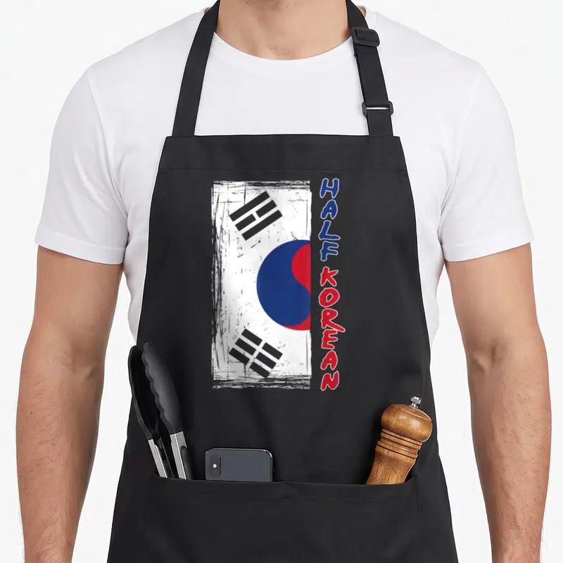 Tablier de cuisine noir avec drapeau coréen stylisé et texte Half Korean vertical rouge et bleu.