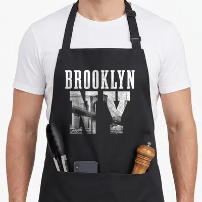 Tablier de cuisine noir avec l'inscription BROOKLYN NY et une illustration du pont Brooklyn en noir et blanc.