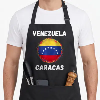Tablier de cuisine noir avec le drapeau Venezuela Caracas en cercle éclaboussé jaune bleu et rouge et texte blanc vintage.