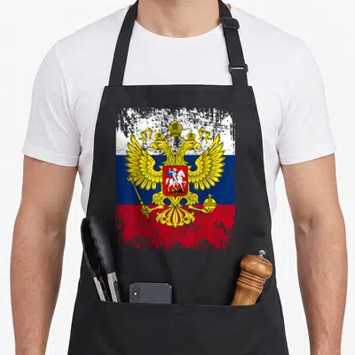 Tablier de cuisine noir avec le drapeau russe et l'aigle bicéphale doré sur fond texturé.