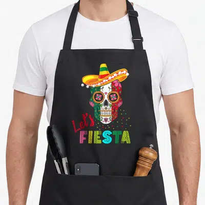 Tablier de cuisine noir avec un crâne coloré portant un sombrero et l'inscription Let's Fiesta Fiesta.