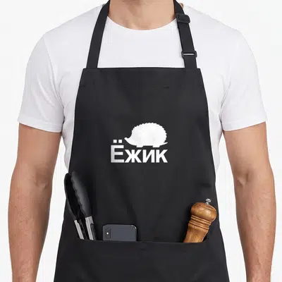 Tablier de cuisine noir avec silhouette d'hérisson et texte en lettres blanches cyrilliques.