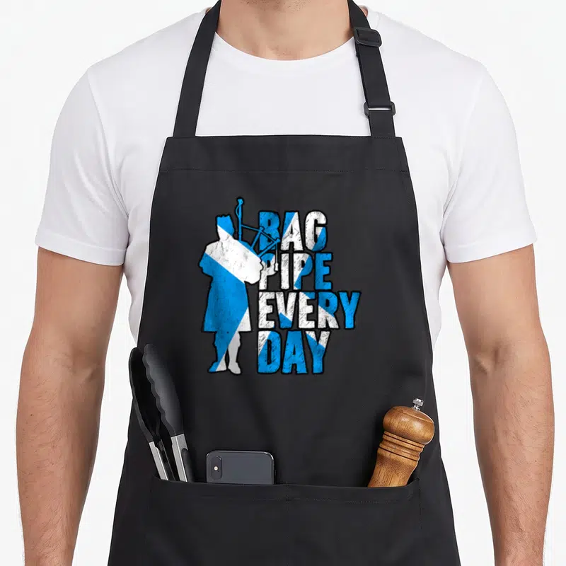Tablier de cuisine noir avec silhouette de cornemuseur et texte Bag Pipe Every Day aux couleurs du drapeau écossais.