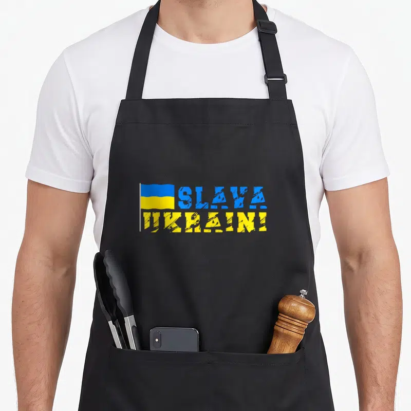 Tablier de cuisine noir avec drapeau ukrainien et texte Slava Ukraini en bleu et jaune texturé.