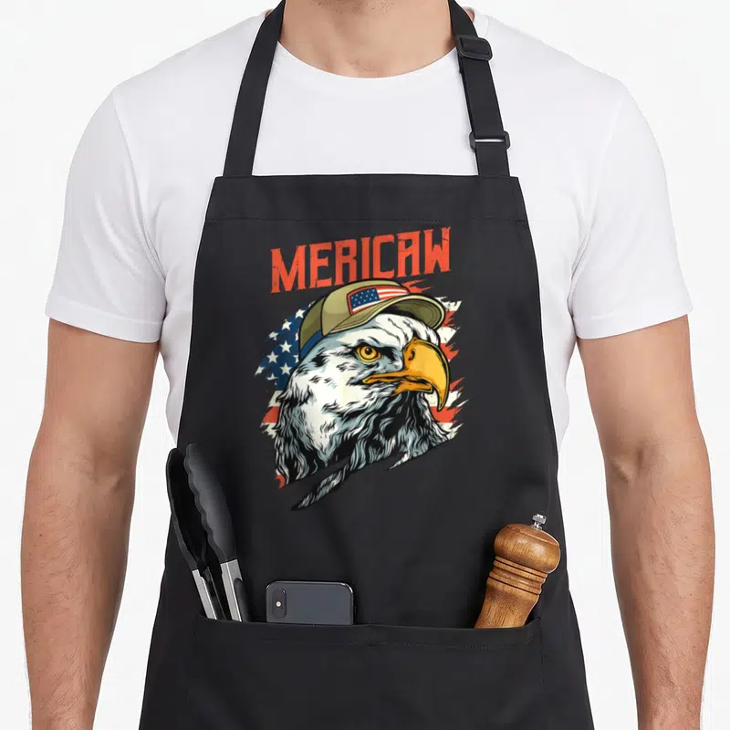 Tablier de cuisine noir avec illustration d'un aigle à tête blanche portant une casquette ornée du drapeau américain sous le mot Mericaw.