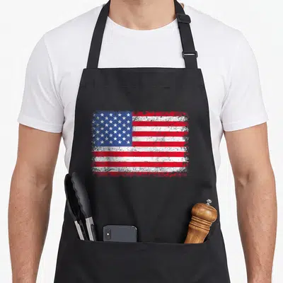 Tablier de cuisine noir avec un drapeau américain imprimé en style vintage délavé rouge blanc et bleu.