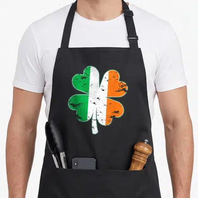 Tablier de cuisine noir avec un grand trèfle aux couleurs vert, blanc et orange du drapeau irlandais.
