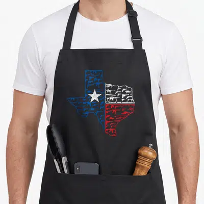 Tablier de cuisine noir avec une carte du Texas aux couleurs du drapeau formée par des silhouettes d'armes.