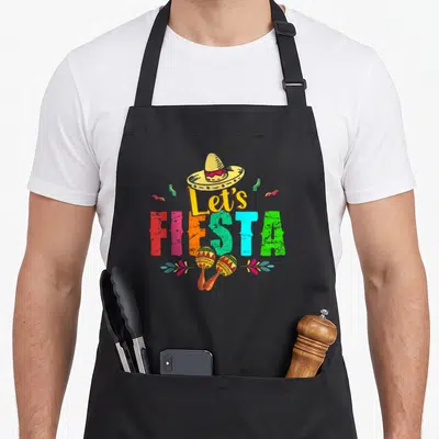 Tablier de cuisine noir avec inscription Let's Fiesta, un sombrero jaune et deux maracas décorés de motifs géométriques colorés.