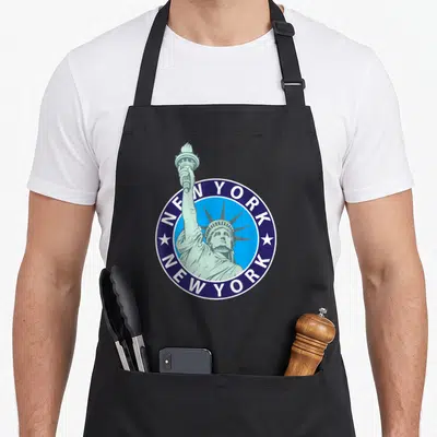Tablier de cuisine noir avec un logo circulaire bleu et vert représentant la Statue de la Liberté de New York City.