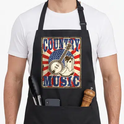 Tablier de cuisine noir avec illustration vintage de banjo, bottes blanches et texte Country Music en bleu et rouge.