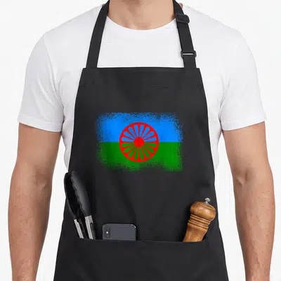 Tablier de cuisine noir avec le drapeau Romani aux bandes bleue et verte et une roue rouge centrale.
