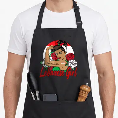 Tablier de cuisine noir avec illustration Lebanese Girl, drapeau Liban, roses rouges et blanches, inscription Unbreakable en rouge.