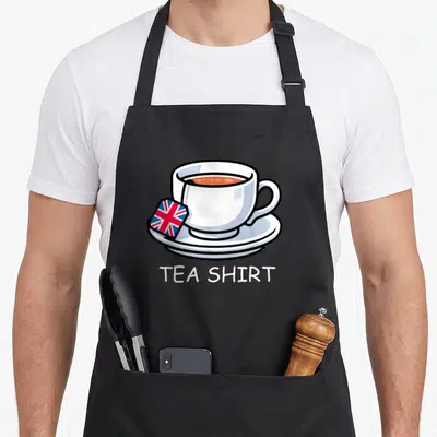 Tablier de cuisine noir avec illustration de tasse de thé et étiquette Union Jack portant le texte TEA SHIRT