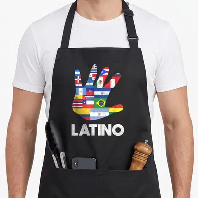Tablier de cuisine noir avec main colorée aux drapeaux latino-américains et le mot LATINO en blanc texturé.