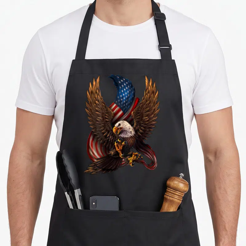 Tablier de cuisine noir avec aigle aux ailes déployées et drapeau américain en arrière-plan.