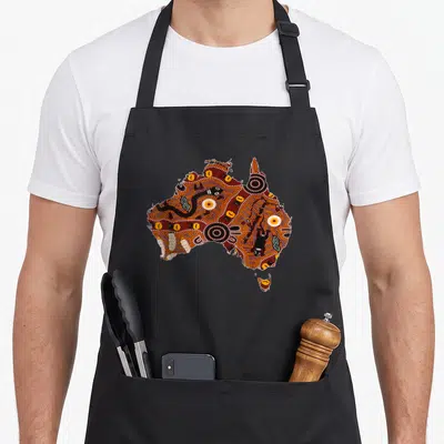 Tablier de cuisine noir avec carte d'Australie en art aborigène pointilliste orange et noir.