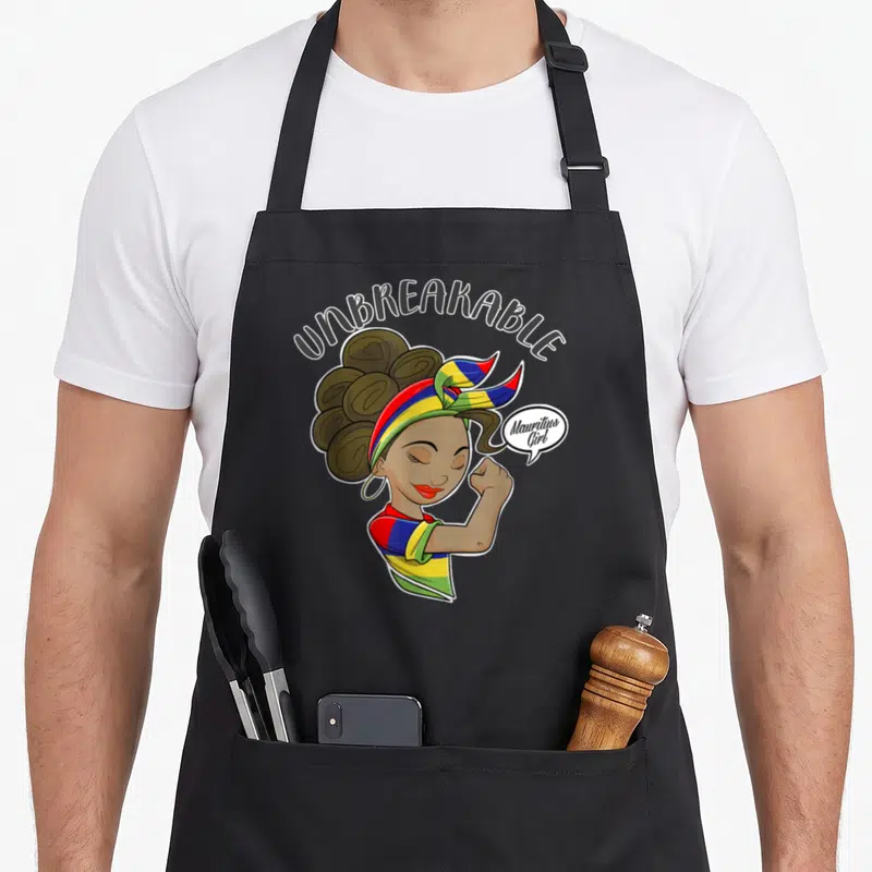 Tablier de cuisine noir avec une illustration d'une femme portant un bandeau aux couleurs du drapeau de l'île Maurice et le texte Unbreakable.