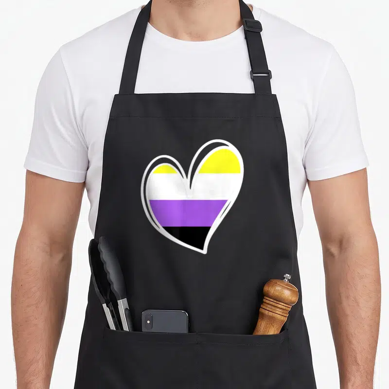 Tablier de cuisine noir avec un grand cœur aux bandes jaunes blanches violettes et noires représentant l'identité Enby non binaire