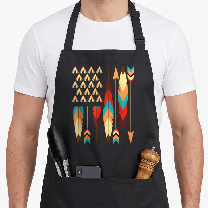Tablier de cuisine noir avec des teepees colorés et des flèches décoratives inspirées de l'art tribal américain.