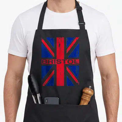 Tablier de cuisine noir avec drapeau Union Jack vintage et le mot Bristol imprimé en gris au centre.