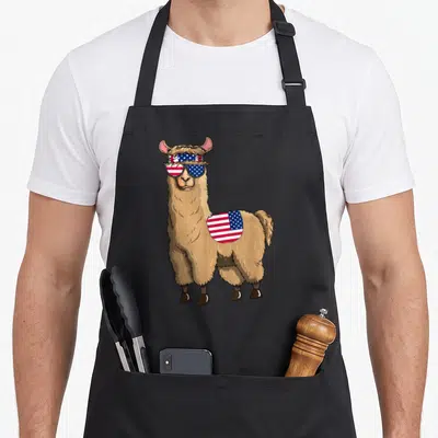 Tablier de cuisine noir avec illustration d'un alpaga portant des lunettes au drapeau américain et une tache patriotique sur le flanc.