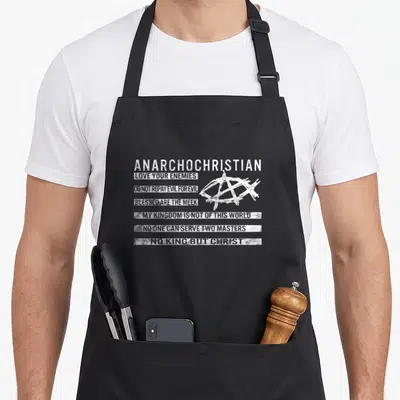 Tablier de cuisine noir avec inscription Anarchochrétien et logo Ichthys en typographie blanche délavée style drapeau.