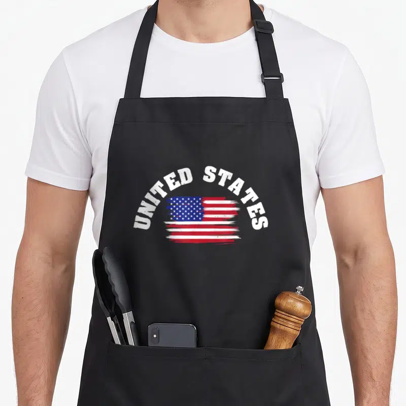 Tablier de cuisine noir avec le drapeau des United States et texte blanc en arc de cercle.