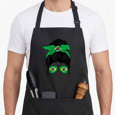 Tablier de cuisine noir avec illustration d'une femme au chignon portant un nœud vert et jaune et des lunettes aux motifs brésiliens.