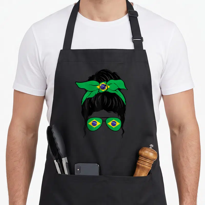 Tablier de cuisine noir avec illustration d'une femme au chignon portant un nœud vert et jaune et des lunettes aux motifs brésiliens.