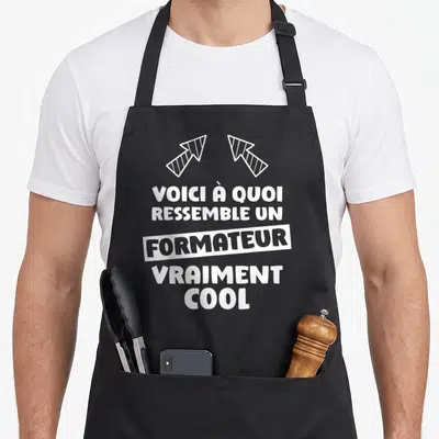 Tablier de cuisine noir avec le texte blanc Voici à quoi ressemble un formateur vraiment cool et deux flèches stylisées en haut.