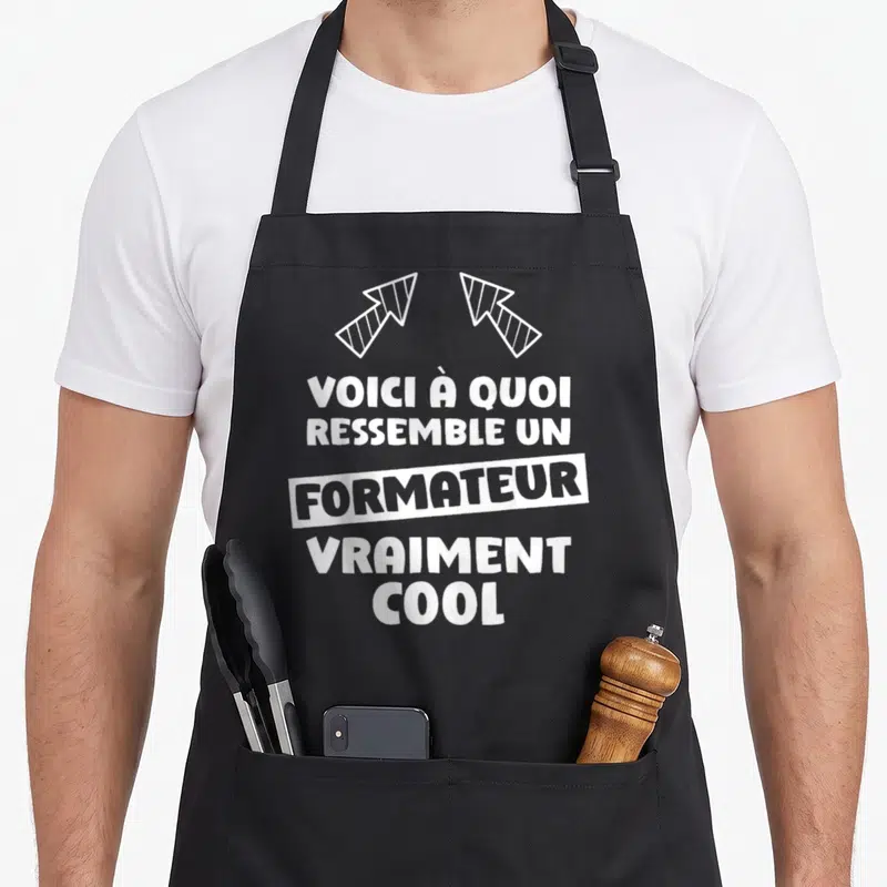 Tablier de cuisine noir avec le texte blanc Voici à quoi ressemble un formateur vraiment cool et deux flèches stylisées en haut.
