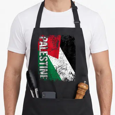 Tablier de cuisine noir avec drapeau Palestine stylisé et inscription verticale PALESTINE en blanc.