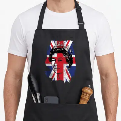 Tablier de cuisine noir avec portrait de la Reine d'Angleterre sur fond de drapeau Union Jack aux couleurs vives.