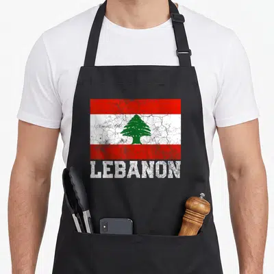 Tablier de cuisine noir avec drapeau Lebanon vintage, cèdre vert et texte Lebanon en blanc déstructuré.