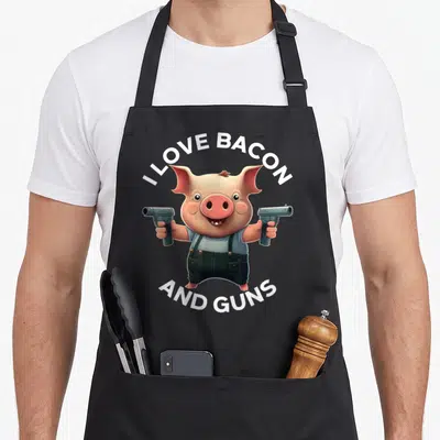 Tablier de cuisine noir avec un cochon cartoon tenant deux pistolets et portant une salopette.