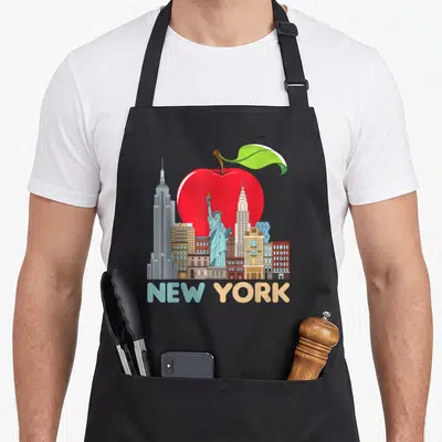 Tablier de cuisine noir avec illustration du Big Apple et des monuments new-yorkais en couleurs vives.