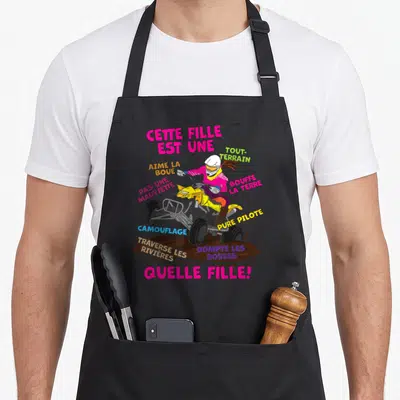 Tablier de cuisine noir avec illustration colorée d'une fille pilotant un quad jaune dans la boue.
