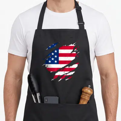 Tablier de cuisine noir avec un motif représentant un drapeau américain aux bords effilochés et aux couleurs éclatantes.