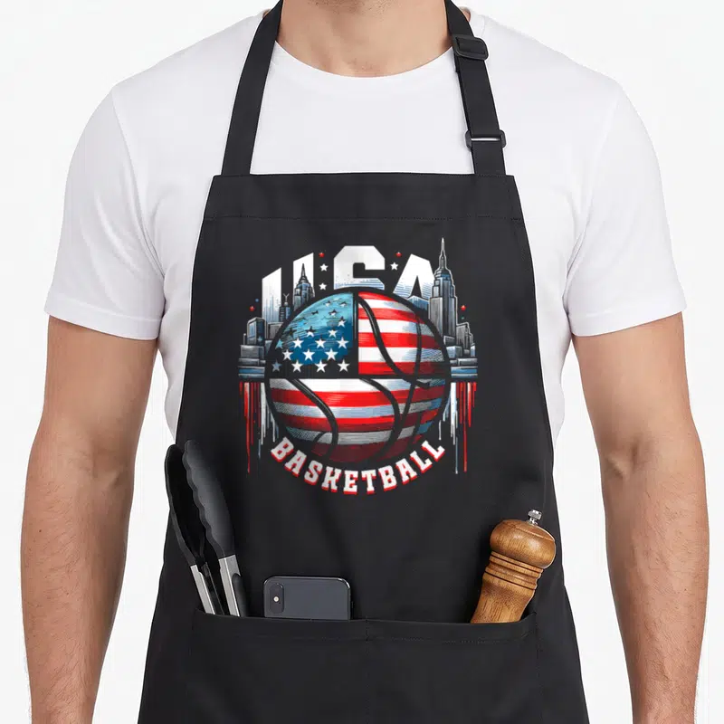 Tablier de cuisine noir avec un ballon de basket aux couleurs du drapeau USA et un skyline en arrière-plan.
