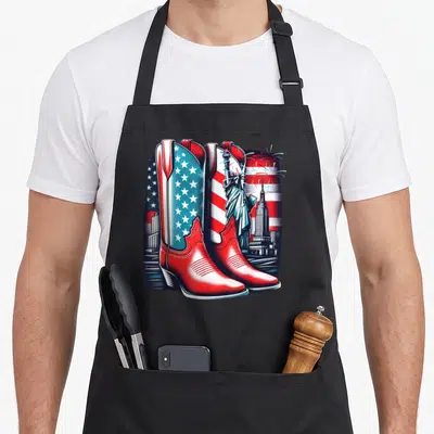 Tablier de cuisine noir avec bottes rouges, drapeau américain et monuments emblématiques des États-Unis imprimés en couleur.