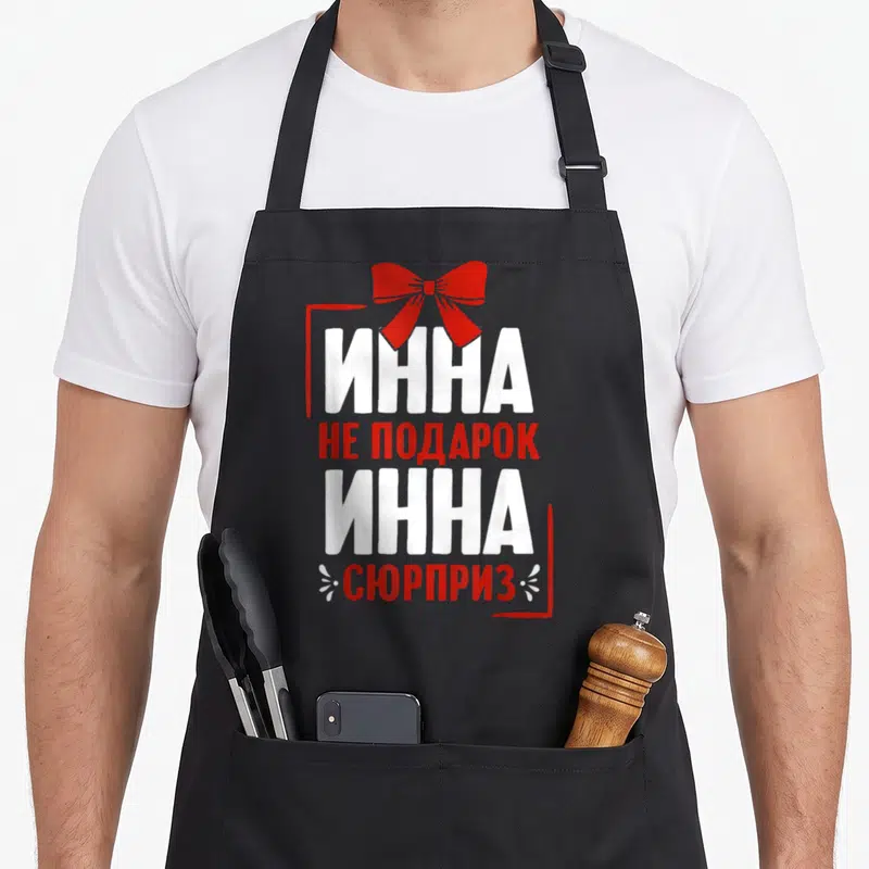 Tablier de cuisine noir avec inscription russe blanche et rouge et un nœud ruban rouge en haut du motif.