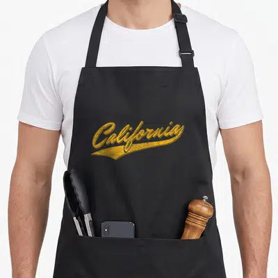 Tablier de cuisine noir avec l'inscription California en lettres dorées style logo sportif vintage.