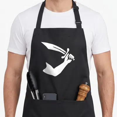 Tablier de cuisine noir avec une illustration blanche d'une main tenant un sabre en forme de drapeau pirate stylisé.