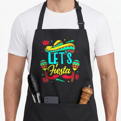 Tablier de cuisine noir avec un sombrero, des maracas et le texte Let's Fiesta en lettres turquoise et jaunes.