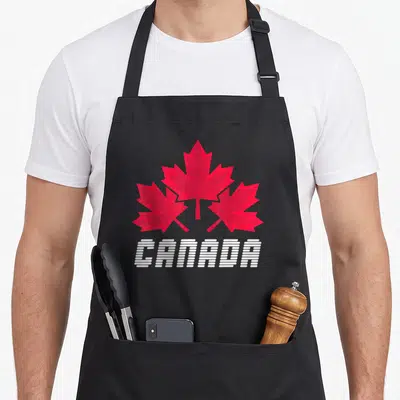 Tablier de cuisine noir avec trois feuilles d'érable rouges et le texte CANADA en blanc stylisé
