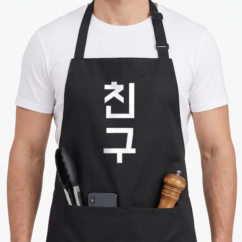 Tablier de cuisine noir avec l'inscription blanche Chingu en caractères Coréens verticaux.