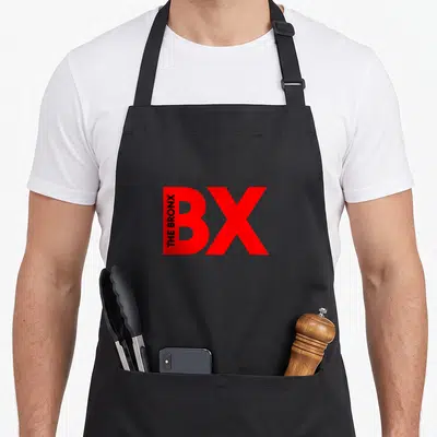 Tablier de cuisine noir avec le logo BX The Bronx imprimé en rouge vif et texte vertical noir sur la lettre B.